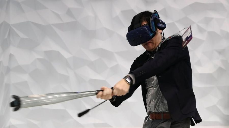 Seorang pria bermain baseball mengenakan perangkat VR di dalam stan HTC di Mobile World Congress di Barcelona, Spanyol 25 Februari 2019. (REUTERS / Sergio Perez)