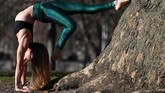 Selain pengunjung yang memadu kasih atau turis yang berfoto, taman ini juga diramaikan oleh pengunjung yang datang untuk berolahraga, salah satunya yoga. (REUTERS/Toby Melville)