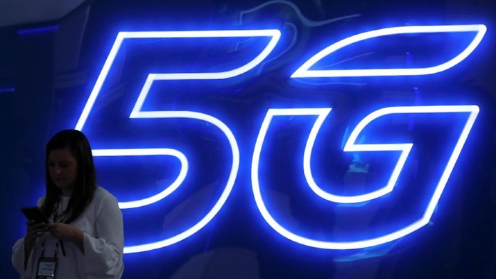 Seorang wanita melihat ponselnya di sebelah tanda 5G di Mobile World Congress di Barcelona, Spanyol, 25 Februari 2019. (REUTERS / Sergio Perez)