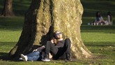 Sepasang kekasih menikmati hangatnya matahari musim semi di Taman St James, London, Inggris. (Niklas HALLE'N / AFP)