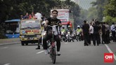 Seorang suporter Timnas Indonesia mengikuti arak-arakan dengan menggunakan sepeda. (CNN Indonesia/Adhi Wicaksono)