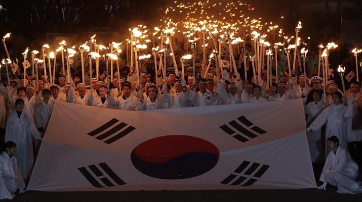 Warga Korea Selatan membawa obor dan bendera nasional ketika mereka berbaris di jalan selama upacara peragaan ulang Hari Gerakan Kemerdekaan Pertama Maret, peringatan pemberontakan 1919 melawan pemerintahan kolonial Jepang, di Cheonan, Korea Selatan, Kamis, 28 Februari, 2019. (AP / Lee Jin-man)