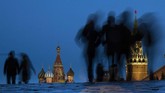 Orang-orang berjalan melewati Red Square setelah matahari terbenam di Moskow, Rusia. St. Basil terlihat di sebelah kiri, sementara Menara Spasskaya di sebelah kanan. (AP/Alexander Zemlianichenko)