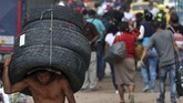 Seorang pria yang menuju Venezuela membawa ban-ban bekas melewati perbatasan dekat Jembatan Internasional Simon Bolivar di La Parada Kolombia. (AP/Martin Mejia)