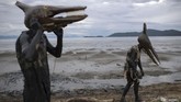 Para penggembira mengenakan kostum Pterodactyl di pesta karnaval lumpur