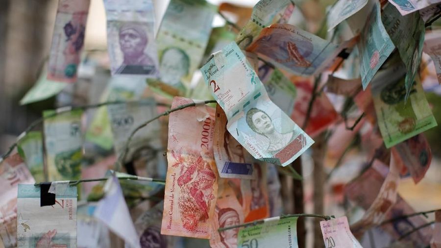 A man walks past Venezuelan bolivar notes hung to resemble a tree, in Caracas, Venezuela March 6, 2019. REUTERS/Carlos Garcia Rawlins
