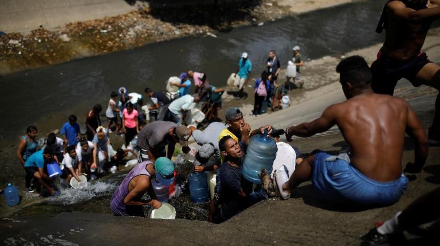 Akibat padamnya listrik memaksa warga Venezuela berebut mengambil air dari saluran limbah yang masuk ke Sungai Guaire di Caracas, Venezuela