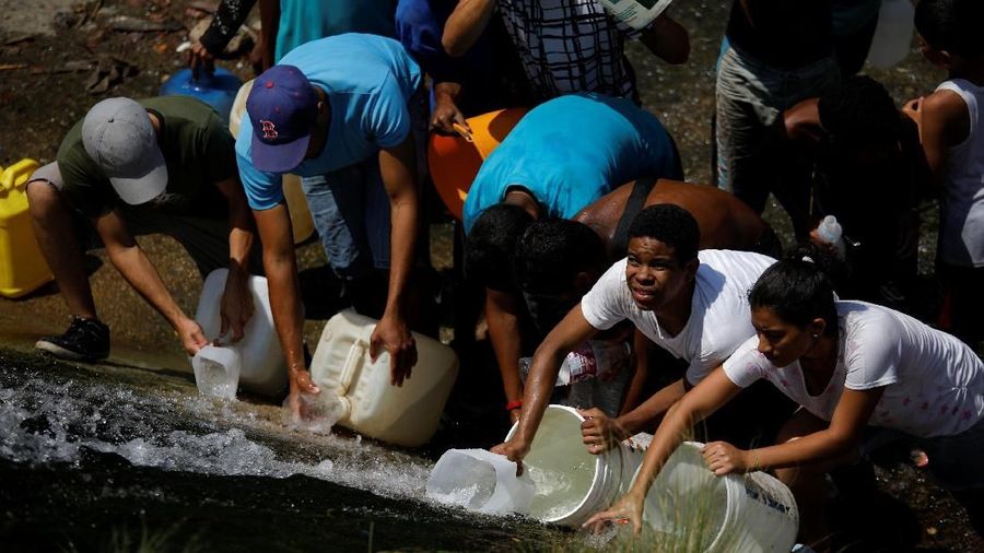 Akibat padamnya listrik memaksa warga Venezuela berebut mengambil air dari saluran limbah yang masuk ke Sungai Guaire di Caracas, Venezuela