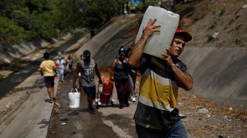 Akibat padamnya listrik memaksa warga Venezuela berebut mengambil air dari saluran limbah yang masuk ke Sungai Guaire di Caracas, Venezuela