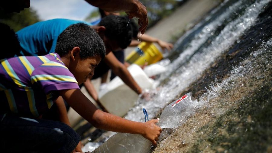 Akibat padamnya listrik memaksa warga Venezuela berebut mengambil air dari saluran limbah yang masuk ke Sungai Guaire di Caracas, Venezuela