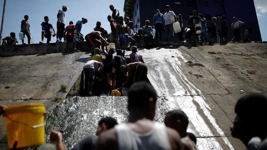 Akibat padamnya listrik memaksa warga Venezuela berebut mengambil air dari saluran limbah yang masuk ke Sungai Guaire di Caracas, Venezuela