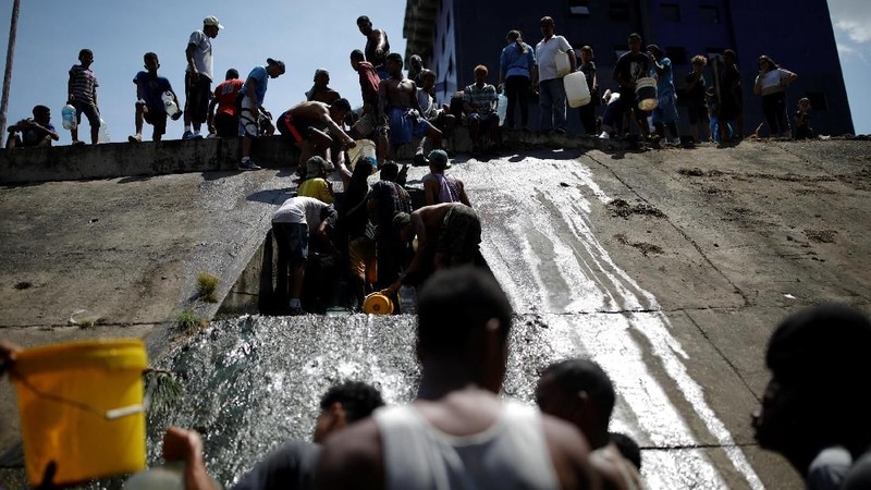 Akibat padamnya listrik memaksa warga Venezuela berebut mengambil air dari saluran limbah yang masuk ke Sungai Guaire di Caracas, Venezuela