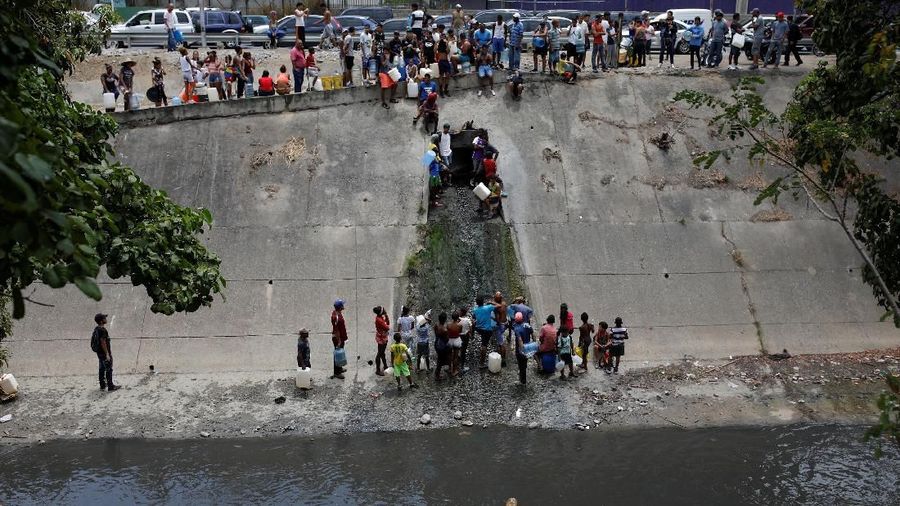 Akibat padamnya listrik memaksa warga Venezuela berebut mengambil air dari saluran limbah yang masuk ke Sungai Guaire di Caracas, Venezuela