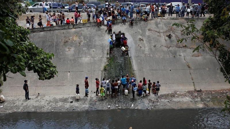 Akibat padamnya listrik memaksa warga Venezuela berebut mengambil air dari saluran limbah yang masuk ke Sungai Guaire di Caracas, Venezuela