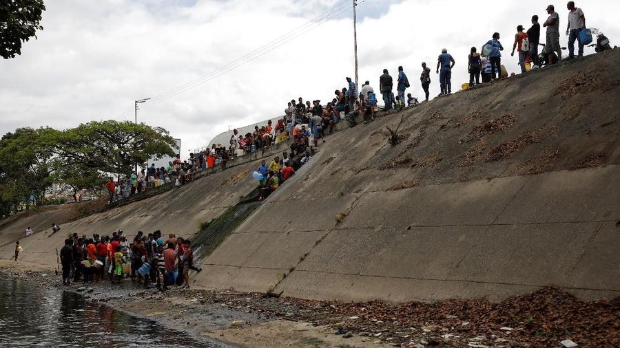 Akibat padamnya listrik memaksa warga Venezuela berebut mengambil air dari saluran limbah yang masuk ke Sungai Guaire di Caracas, Venezuela