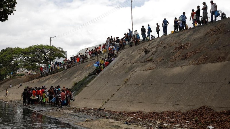 Akibat padamnya listrik memaksa warga Venezuela berebut mengambil air dari saluran limbah yang masuk ke Sungai Guaire di Caracas, Venezuela