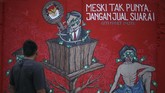 Warga melihat mural bertema Pemilu 2019 di Stadion Kridosono, DI Yogyakarta. Pesan yang disampaikan dalam Mural itu mengajak warga menolak politik uang. (ANTARA FOTO/Hendra Nurdiyansyah)