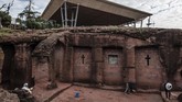 Warga lokal berdiri di sebelah Gereja Santo Mercurius yang tertutup penampungan yang terancam erosi. (Photo by EDUARDO SOTERAS / AFP)