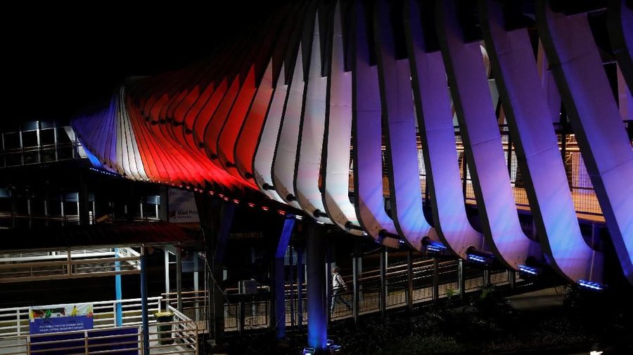 People walk on a pedestrian bridge, illuminated with colors of New Zealand's national flag as a tribute to victims of the mosque shootings, in Christchurch, in Jakarta, Indonesia, March 17, 2019. REUTERS/Willy Kurniawan