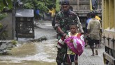 Seorang prajurit TNI menuntun seorang anak yang akan mengungsi akibat banjir bandang di Sentani, Jaya Pura, Papua, Senin (18/3/2019). ANTARA FOTO/Zabur Karuru