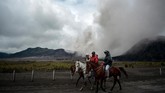 Tiga orang menunggang kuda dengan latar belakang Gunung Bromo yang menyemburkan abu vulkanis di Probolinggo, Jawa Timur, 15 Maret 2019. (ANTARA FOTO/Umarul Faruq)