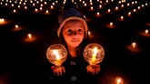 Seorang bocah perempuan menyalakan lilin dan menghadiri acara yang menyebarkan pesan kedamaian pada dunia di Kathmandu, Nepal. (REUTERS/Navesh Chitrakar)