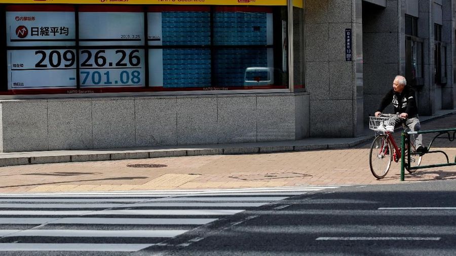 A man stands in front of an electronic board showing the Nikkei stock index outside a brokerage in Tokyo, Japan, March 25, 2019. REUTERS/Kim Kyung-hoon