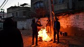 Sekelompok pria pengangguran membakar kardus untuk menghangatkan tubuh kala pagi mulai menjelang di Gaza. (REUTERS/Dylan Martinez)