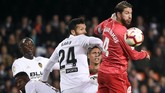 Kapten Real Madrid Sergio Ramos (kanan) berduel dengan bek Valencia Ezequiel Garay. Garay kemudian mencetak gol kedua Valencia pada menit ke-83. (JOSE JORDAN / AFP)