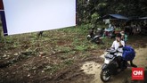 Kain putih yang dijadikan layar dibentangkan di halaman pemilik hajat. Semalam suntuk film diputar hingga dini hari. (CNN Indonesia/ Hesti Rika)
