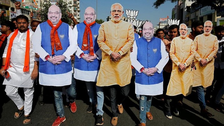 pemilu india Supporter of India's ruling Bharatiya Janata Party (BJP) wearing cut-outs of Prime Minister Narendra Modi and the party president Amit Shah walk during an election campaign in Ahmedabad, India, April 11, 2019. REUTERS/Amit Dave TPX IMAGES OF THE DAY