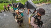 Personel Polri mengawal sejumlah pekerja pengangkut barang (porter) menyeberangi sungai saat membawa logistik Pemilu serentak 2019 ke dua desa terpencil di kaki Pegunungan Meratus, Kabupaten Hulu Sungai Tengah, Kalimantan Selatan, Minggu (14/4). (ANTARA FOTO/Bayu Pratama S/wsj).