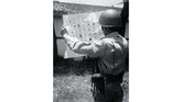 Seorang anggota APRI sedang memperhatikan surat suara yang bergambar lambang-lambang partai politik sebelum dicoblos, 29 September 1955. (Sumber: ANRI)