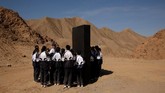 Para siswa berkumpul di sekitar lempengan hitam yang mewakili materi dari Mars di Gurun Gobi, pangkalan simulasi C-Space Project Mars, China. (REUTERS/Thomas Peter)