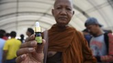 Seorang biksu Buddha menunjukkan botol minyak ganja untuk obat yang telah terdaftar di Festival Ganja Pan Ram, 19 April 2019. (AFP/Lillian SUWANRUMPHA)