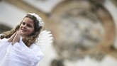 Di Brasil, seorang gadis berdandan bak malaikat yang berjalan di atas permadani serbuk gergaji saat prosesi Paskah yang menggambarkan kebangkitan Kristus di kota bersejarah Ouro Preto, Minggu (21/4). (Photo by Douglas MAGNO / AFP)