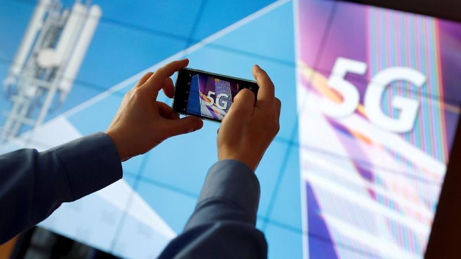 FILE PHOTO: A journalist uses his mobile phone to take a picture of the 5G logo prior to the auction of spectrum for 5G services at the Bundesnetzagentur head quarters in Mainz, Germany, March 19, 2019.  REUTERS/Kai Pfaffenbach/File Photo
