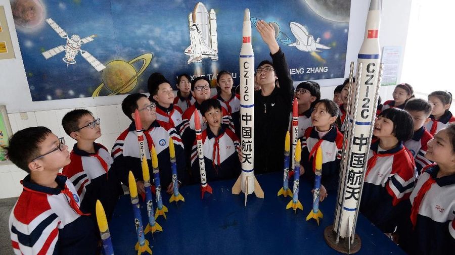 Students listen to their teacher introducing a model of the Long March-2C rocket at a primary school on China’s Space Day in Handan, Hebei province, China April 24, 2019. China Daily via REUTERS  ATTENTION EDITORS - THIS IMAGE WAS PROVIDED BY A THIRD PARTY. CHINA OUT.