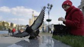 Di pusat kota Kiev, Ukraina, Seorang perempuan memberi makan burung merpati. (AP Photo/Sergei Grits)