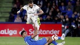 Striker Real Madrid, Karim Benzema, menccoba melewati adangan pemain Getafe. Benzema total hanya melepaskan total tiga tembakan dan cuma satu yang tepat sasaran. (REUTERS/Sergio Perez)