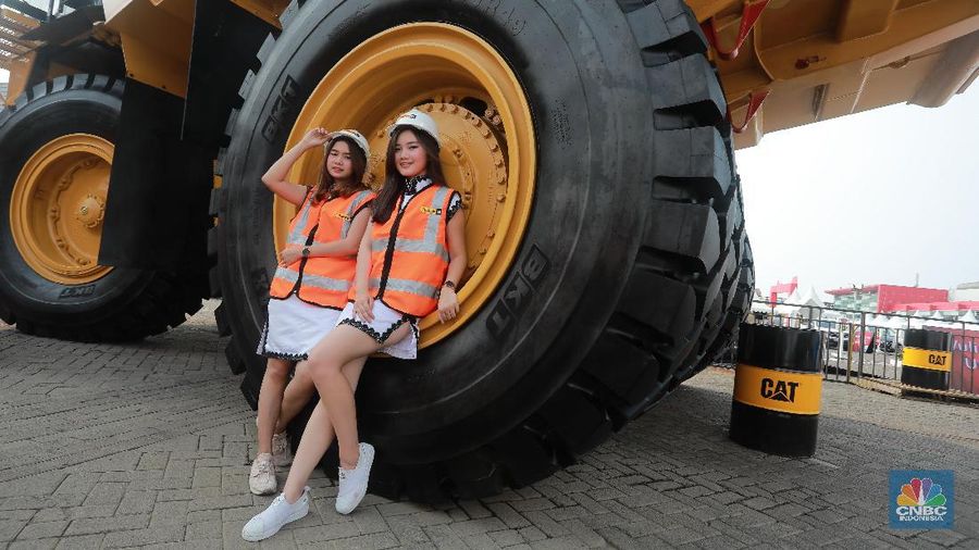Model berpose di depan mobil alat berat jenis Caterpillar berada IIMS 2019, JIExpo Kemayoran, Jakarta Pusat, Jumat (26/4).  Kendaraan tambang Caterpillar 777D dengan tinggi sekitar 6 meter ini didominasi warna kuning dan hitam dan didatangkan oleh Trakindo Utama Caterpillar 777D. Mobil ini dijual Rp13 milliar. Banyak pengunjung yang datang dan berfoto di depan truk raksasa.  Tujuan ditampilkan nya mobil alat berat untuk pertambangan itu bertujuan untuk memberikan edukasi kepada warga tentang alat berat dan fungsinya. (CNBC Indonesia/Muhammad Sabki)