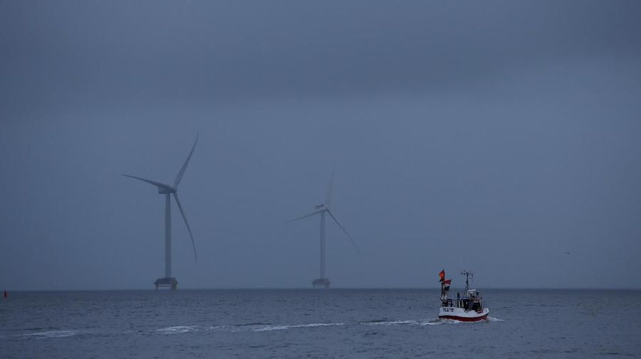 Sebuah kapal nelayan berlayar di depan turbin angin melalui Kanal Thyboron di Jutland, Denmark, 14 Maret 2019. (REUTERS / Andrew Kelly)