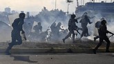 Anggota Pasukan Keamanan Bolivarian yuang setia pada pemerintahan Presiden Nicolas Maduro tengah diantara kepulan asap gas air mata yang ditembakkan pendukung pemimpin oposisi Venezuela yang mendeklarasikan diri sebagai presiden Juan Guaido. (Photo by Yuri CORTEZ / AFP)