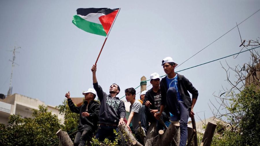 Palestinians climb over a tree during a rally marking International Workers' Day, or Labour Day, in Gaza City May 1, 2019. REUTERS/Mohammed Salem