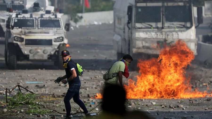 Opposition supporters walk in front of military vehicles during clashes with security forces following a rally against the government of Venezuela's President Nicolas Maduro and to commemorate May Day in Caracas, Venezuela May 1, 2019. REUTERS/Manaure Quintero NO RESALES. NO ARCHIVES