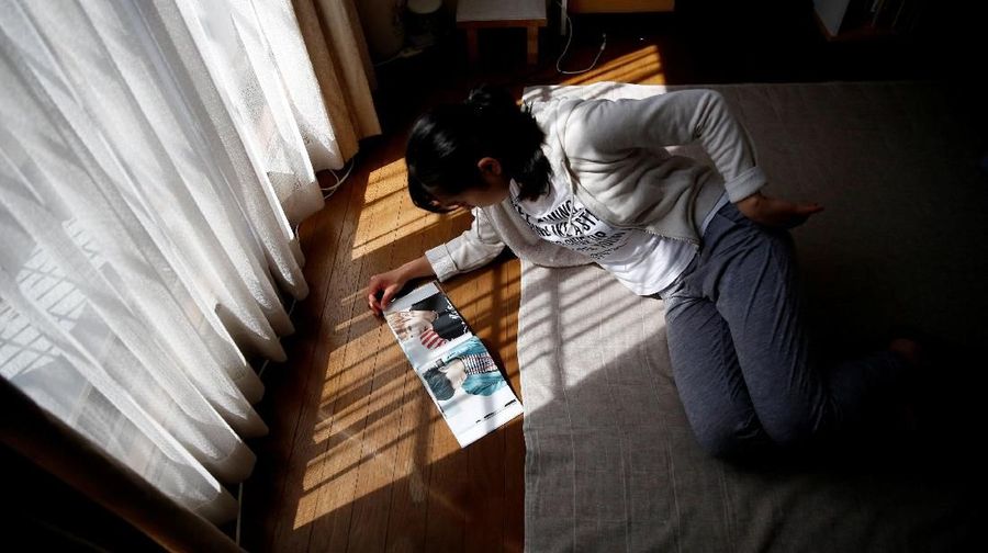 Nao Niitsu, 19, college freshman from Tokyo, who wants to be a K-pop star, looks at BTS's photo book in her room in Tokyo, Japan, March 20, 2019.