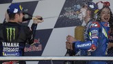 Pebalap Yamaha Maverick Vinales (kiri) menyemprotkan sampanye ke arah Alex Rins di atas podium MotoGP Spanyol 2019. (JORGE GUERRERO / AFP)