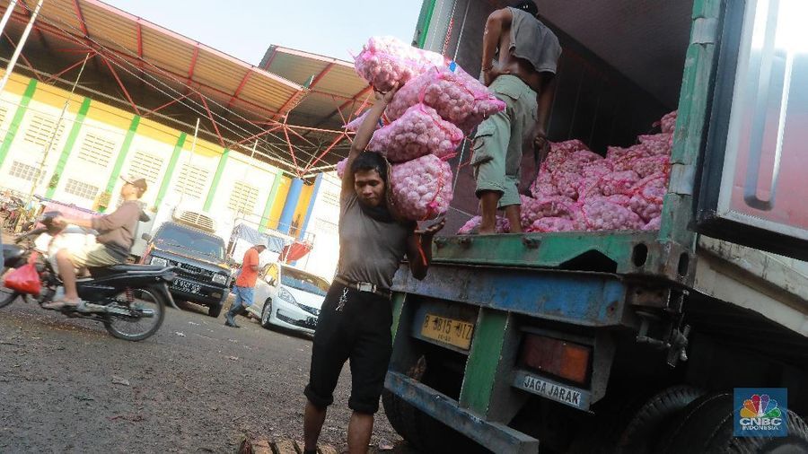 Kuli panggul mengangkat karung bawang putih di Pasar Kramat jati,  Jakarta Timur, Selasa 7/5. Pedagang Los Eceran dikawasan pasar Kramat jati menjual bawang putih Rp 35.000 per kilogram turun dari harga sebelumnya Rp45.000 karena pasokan bawang putih sudah sedikit stabil. Harga bawang putih yang dijual Eceran seharga Rp50. 000 sampai Rp60. 000. Harga bawang  merah naik sedikit dari Rp 20.000 menjadi Rp 22. 000 harga Los Eceran. Harga Cabe merah turun menjadi Rp 25.000 turun saat kemarin naik Rp 30.000 sampai Rp 40.000.   (CNBC Indonesia/Muhammad Sabki)