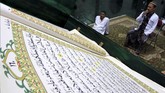 Seorang warga muslim bertadarus membaca Alquran raksasa di Masjid Baiturrahman, Banyuwangi, Jawa Timur, Selasa (7/5). (ANTARA FOTO/Budi Candra Setya)