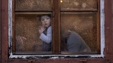 Bocah berusia satu tahun menatap keluar dari balik jendela yang dipenuhi air hujan di kota Sibiu, Rumania. Sibiu sendiri akan menjadi kota penyelenggara pertemuan kepala negara Uni Eropa. (AP Photo/Vadim Ghirda)